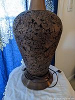 Close-up image showing the bulbous cork-covered body and brass base of the vintage mid-century modern lamp.