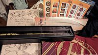 Photo showing authentic Ollivanders wand in black case, maroon Hogwarts hoodie, feather quill pen, Marauder's Map and multiple sticker packages
