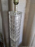 Close-up image of the top half of the glass block floor lamp showing the clear glass blocks and brass lamp socket.