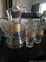 Pitcher with handle and spout, showing wide gold glittery band with dot detail on clear glass