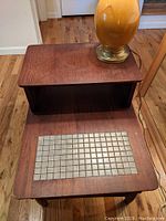 Overview of the table showing tiled inset and wood surface with a lamp base on top.