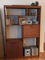 Front view of the teak bookcase showing multiple shelves, cabinet, and drop-down door section.