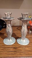 Pair of pewter candlesticks with detailed pattern on base and stem
