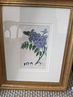 Framed botanical print featuring a purple lilac branch, showing clean white mat and sturdy gold frame