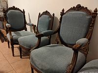 Front view of all four Victorian walnut parlor chairs, showing light blue upholstery and detailed carving.
