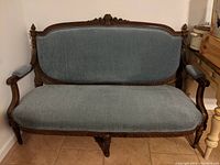 Full view of Victorian walnut settee with blue-grey upholstery showing frame and cushion.