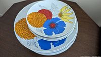 Top view of a stack of vintage rimless plates with colorful floral designs showing dinner plates and salad plates