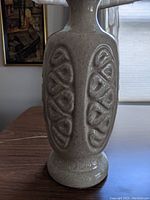 Close-up side view of the white ceramic lamp base showing raised oval geometric relief pattern and speckled glaze finish.