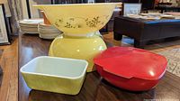 Photo of five vintage Pyrex items including large yellow Shenandoah bowl, red divided casserole with lid, yellow bowl, and green rectangular dish.