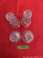 Top view of both pairs of glass candlestick holders on red textured fabric showing their bases and tops.