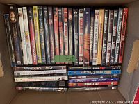 Photo showing over 30 used DVDs in a box, including TV series and movies like The X-Files, Downton Abbey, Ladder 49, Knights Tale, and more.