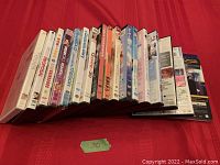 Lot of 17 DVDs standing upright on red surface showing spines and partial covers, all appear to be romantic or romantic comedy film titles.