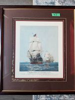Framed vintage lithograph of sailing ships, titled 'The First Journey of Victory 1778', shown with brown matting and wooden frame.