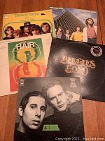 Five vintage vinyl records with visible covers for Beach Boys, Air Supply, Bee Gees, Simon & Garfunkel and Hair albums.