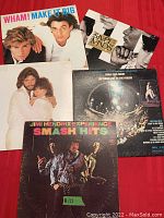 Five vintage vinyl albums laid out on a red background showing front covers from Wham, Simple Minds, Barbra Streisand, Three Dog Night, and Jimi Hendrix Experience.