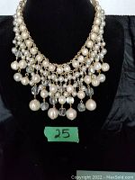 Front view of the bib style necklace prominently showing layered pearl-like beads and crystal-like beads hanging from gold-tone chains.