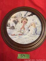 Front of framed collector plate with artwork of praying child and doll, round wooden frame