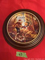 Full view of the framed porcelain collector plate showing a child playing goalie with a teddy bear and dog indoors, winter scene visible outside.