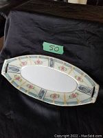 Full view of the oval porcelain dish showing floral, blue geometric and black design with gilded edges