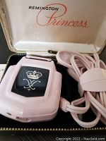 Pink Remington Princess electric shaver in original case showing power cord and emblem on front.