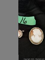 Cameo brooch and one screw back earring showing the size and design details including the classical woman's profile carved in white against a brown background with a beaded border.