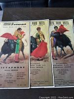 Set of three vintage Spanish bullfighting poster style menus laid out side by side on a dark surface, showing colorful matadors facing bulls and text below describing menu items and event details.