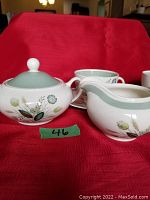 Photo of sugar bowl with lid and creamer pitcher showing the floral decals and pale green rim band.