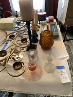 Photo of gold scroll metal votive holder along with various glass and wooden candle holders on table