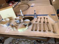 Overview of all items on display including tea cups, figurines, decorative spoons, bells, bowl, and box