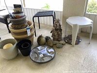 Image of all collections of outdoor yard art, plant pots, plant caddy, and small tables on patio floor.