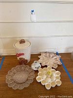 Overview of cookie jar, glass plate, leaf tray, egg holder, and sake bottle on wooden floor against wall