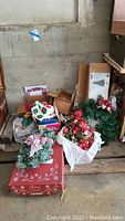 Photo showing collection of Christmas decorations including an assortment of wreaths, boxes, and the artificial tree sum parts packed at the back