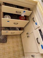 Drawer with various kitchen items including funnels, food wrap boxes, corkscrew, and other utensils.