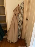 Two outdoor patio umbrellas covered and stored upright indoors.