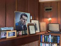 Picture frames arranged on a wooden shelf with wood paneling background, including a large portrait and smaller framed photos and empty frames.