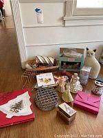 Photo showing various items including a large ceramic cat figurine, angel figurines, pink decorative boxes, a circular metal trivet, pack of Easter bunny display, and a Nikko Christmastime tree-shaped candy dish in box