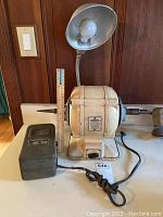 Front angled view of vintage dentist lathe showing main motor housing, spindle, power supply box, and ruler for scale.