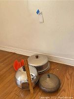 Photo showing metal ice bucket, glass cake plate with metal cover, and metal ashtray positioned on wood floor for scale and condition assessment