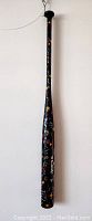 Full-length view of the painted baseball bat suspended against a white wall