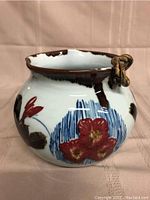 Side view showing floral decoration and brown drip glaze.