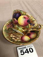 Assembled teacup and saucer on cloth background with lot number card