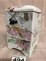 Front angled view of the three stacked antique Chinese porcelain boxes showing hand-painted cranes and cherry blossoms with gold accents.