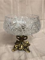 Crystal compote with detailed crystal cut patterns on a decorative brass base, front angle
