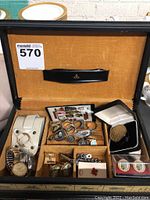 Overview of fabric-lined box containing watches, cufflinks, tie bars and rings