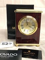Front and side view of Movado desk clock with original box and warranty card visible.