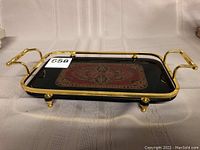 Full view of the rectangular serving tray showing black base with gold metal frame, handles and legs; central Persian carpet design.