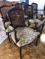 Six wicker back dining chairs grouped together on parquet floor