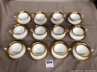 Top-down view of twelve white porcelain teacups each paired with a saucer, arranged in a grid