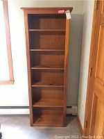 Front view of tall pine wood bookcase showing six fixed shelves.