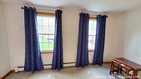 Four dark blue drapery panels with medium blue branch pattern hung on windows showing full length and decoration.